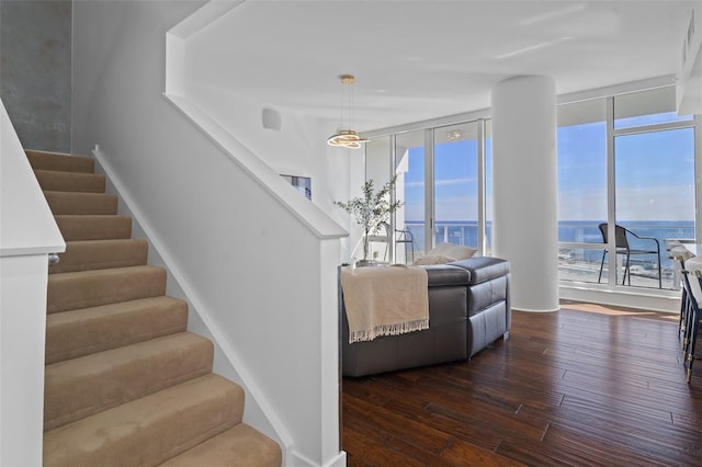 stairway with hardwood / wood-style flooring, floor to ceiling windows, and a water view