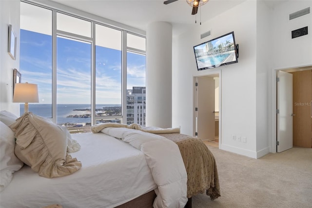 bedroom featuring ceiling fan, light colored carpet, and ensuite bathroom