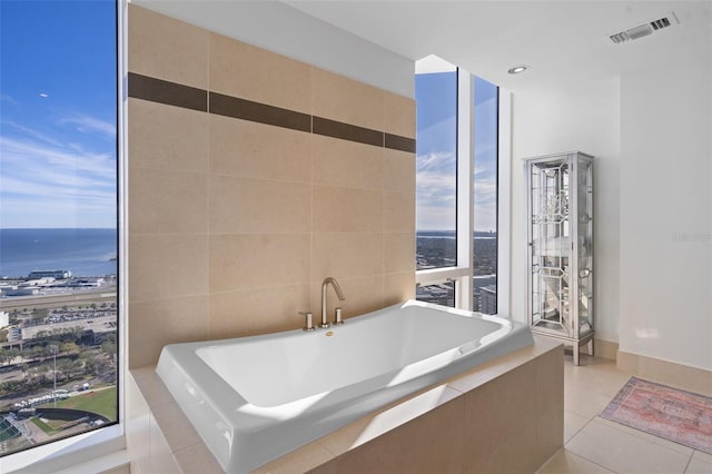 bathroom featuring a water view, tile patterned floors, and tiled tub