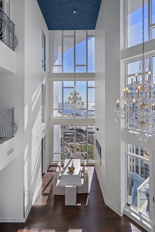 interior space with a towering ceiling, dark hardwood / wood-style floors, and an inviting chandelier