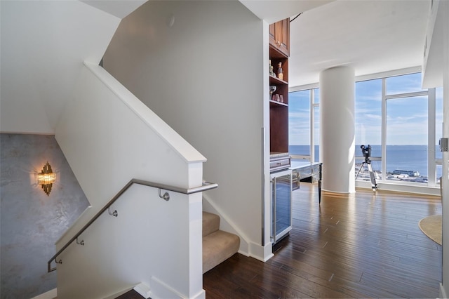 stairway featuring expansive windows, a wealth of natural light, a water view, and hardwood / wood-style flooring