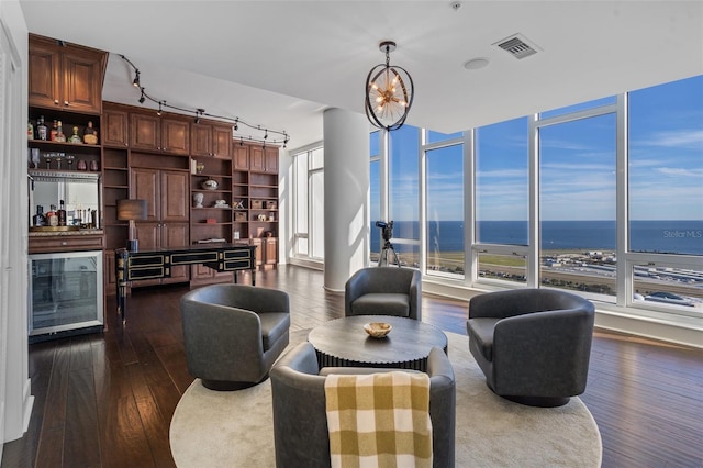 living room featuring a water view, dark wood-type flooring, and a notable chandelier