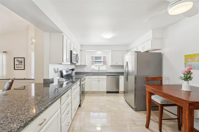 kitchen with white cabinetry, sink, appliances with stainless steel finishes, and dark stone counters