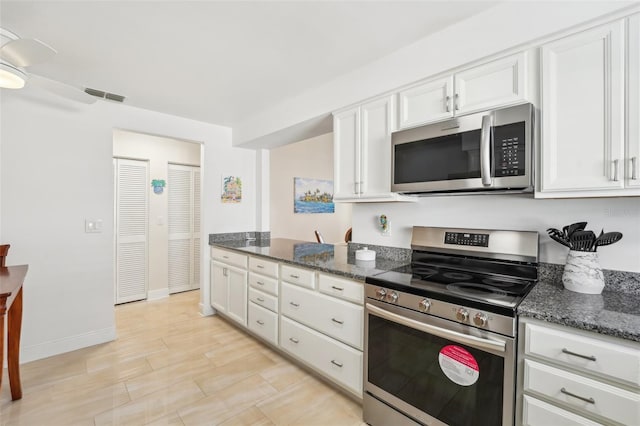 kitchen featuring appliances with stainless steel finishes, white cabinetry, and dark stone counters