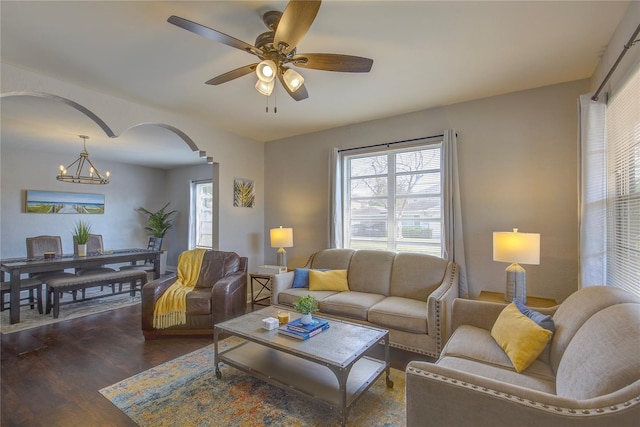 living room featuring arched walkways, ceiling fan with notable chandelier, and wood finished floors