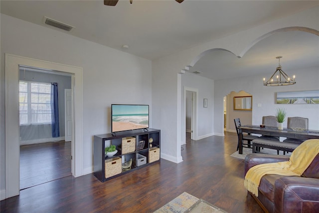 living room with dark hardwood / wood-style floors and ceiling fan with notable chandelier