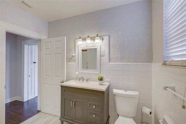 bathroom featuring vanity, wood-type flooring, tile walls, and toilet