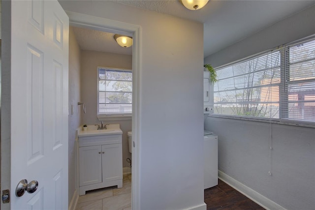 bathroom featuring stacked washer / drying machine, vanity, and a textured ceiling