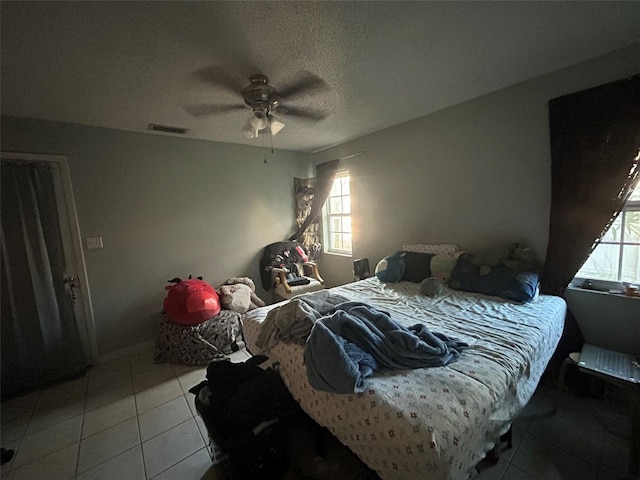 bedroom with tile patterned flooring, ceiling fan, and a textured ceiling