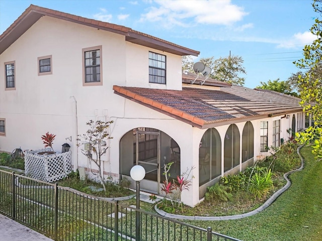 back of property with a lawn and a sunroom