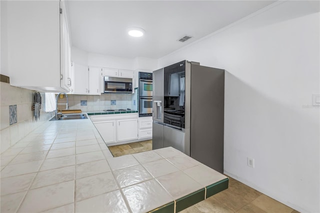 kitchen with white cabinets, tile counters, appliances with stainless steel finishes, and sink