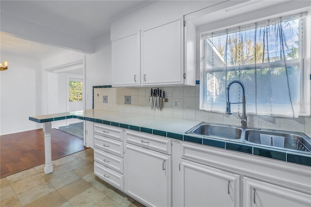 kitchen featuring white cabinets, tile counters, decorative backsplash, and sink