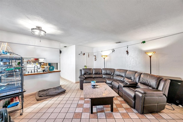 tiled living room with sink and a textured ceiling