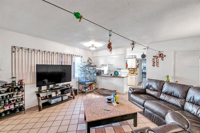 living room featuring sink, light tile patterned flooring, and a textured ceiling