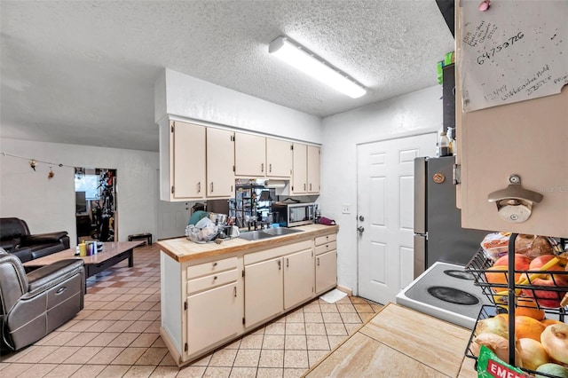 kitchen featuring sink, light tile patterned floors, stainless steel appliances, and a textured ceiling