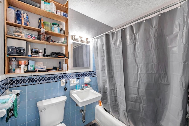 full bathroom featuring shower / bath combination with curtain, a textured ceiling, sink, tile walls, and toilet