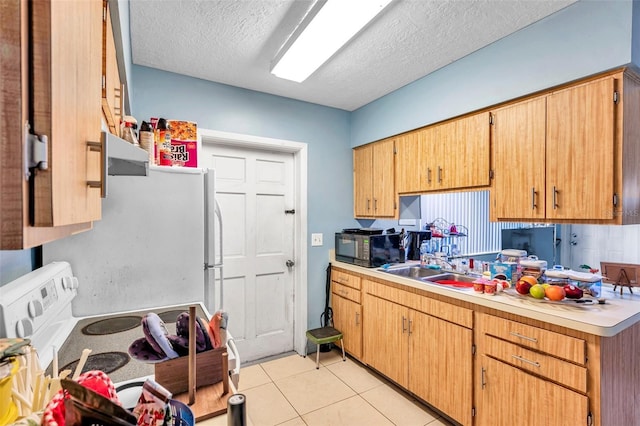 kitchen featuring refrigerator, sink, light tile patterned floors, a textured ceiling, and range