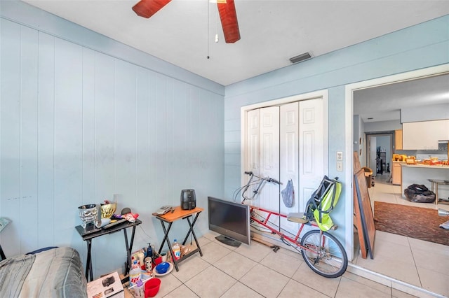 recreation room with ceiling fan, light tile patterned floors, and wooden walls