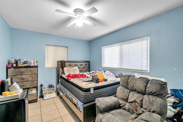 bedroom with ceiling fan, light tile patterned floors, and a textured ceiling