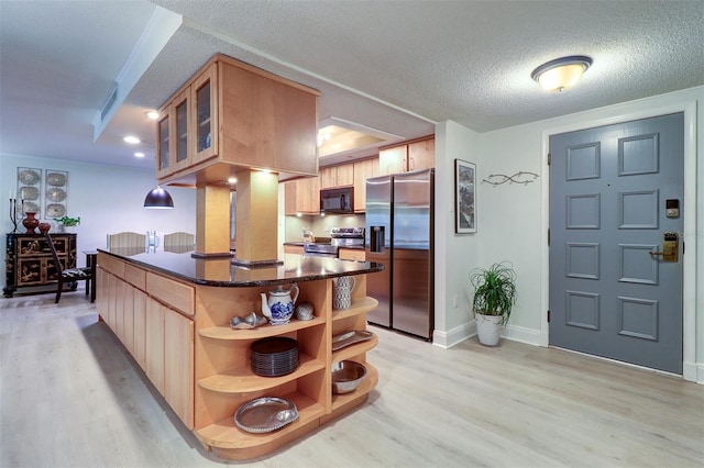 kitchen featuring a textured ceiling, light wood-type flooring, and stainless steel appliances