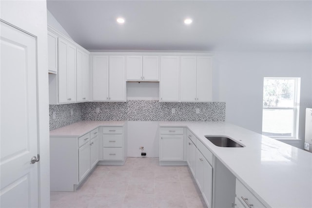 kitchen featuring white cabinets, decorative backsplash, light tile patterned floors, and sink