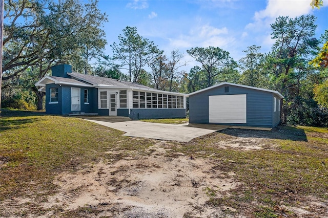 single story home featuring a sunroom, a garage, an outdoor structure, and a front yard