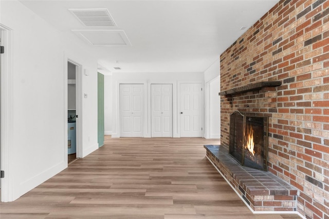 unfurnished living room featuring light hardwood / wood-style flooring and a brick fireplace