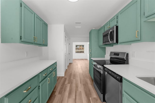 kitchen with light hardwood / wood-style floors, appliances with stainless steel finishes, and green cabinetry