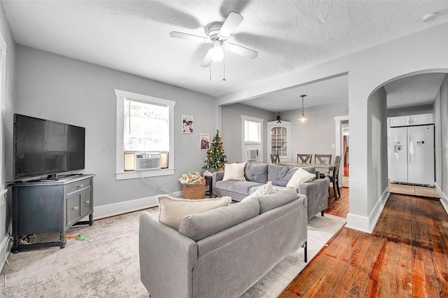 living room featuring hardwood / wood-style flooring, ceiling fan, cooling unit, and a textured ceiling