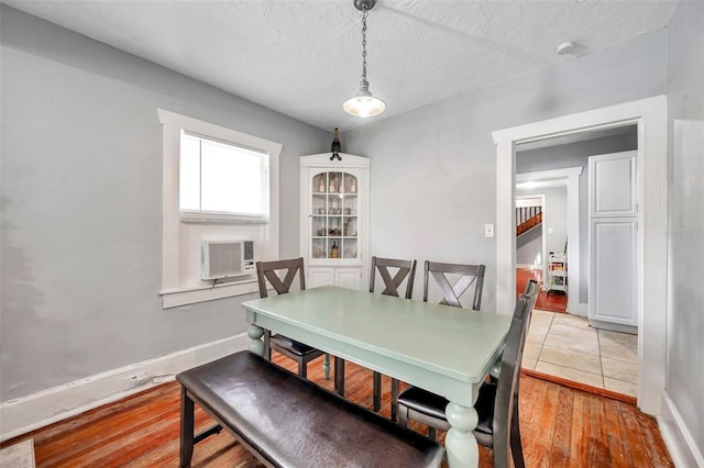 dining room featuring cooling unit, a textured ceiling, and light hardwood / wood-style flooring