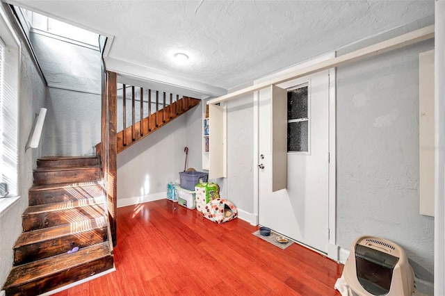 basement featuring wood-type flooring, a textured ceiling, and heating unit