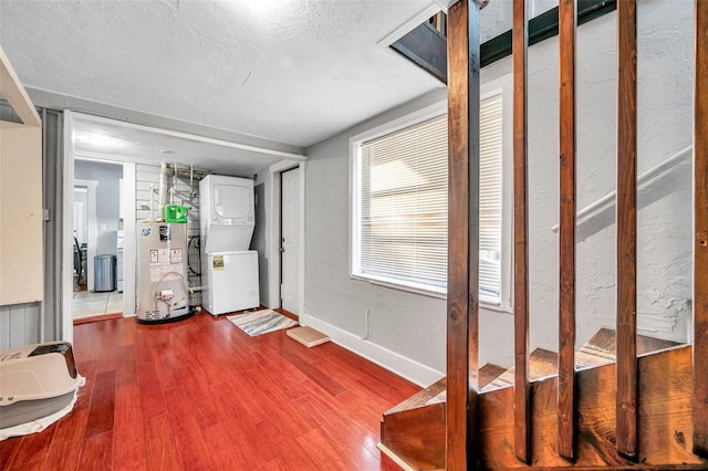 interior space featuring a textured ceiling, stacked washer / dryer, hardwood / wood-style floors, and gas water heater