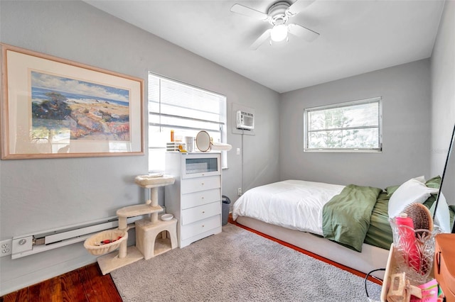 bedroom featuring hardwood / wood-style floors, a wall unit AC, ceiling fan, and a baseboard heating unit