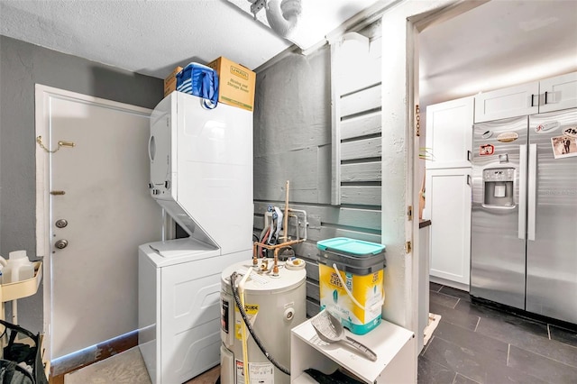 clothes washing area featuring stacked washing maching and dryer, a textured ceiling, and water heater