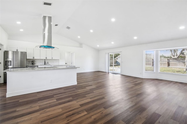 kitchen featuring light stone counters, a center island with sink, stainless steel fridge, white cabinets, and exhaust hood