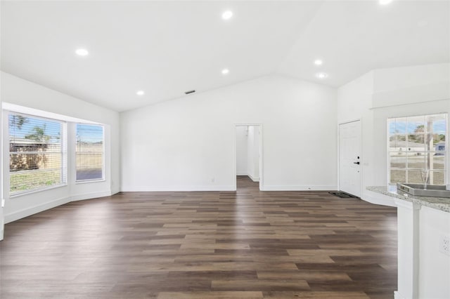 unfurnished living room featuring lofted ceiling, dark wood-type flooring, and a healthy amount of sunlight