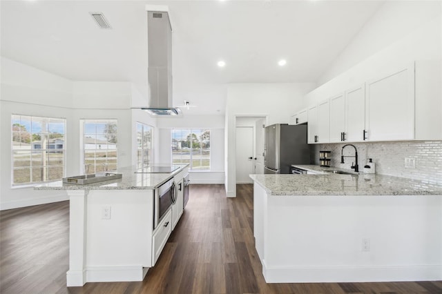 kitchen featuring sink, stainless steel refrigerator, white cabinetry, island range hood, and light stone countertops