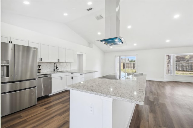 kitchen featuring light stone counters, vaulted ceiling, a kitchen island, stainless steel appliances, and white cabinets