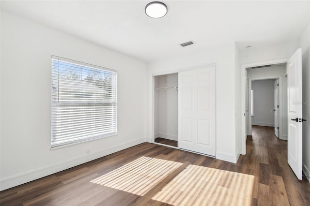 unfurnished bedroom with dark wood-type flooring and a closet