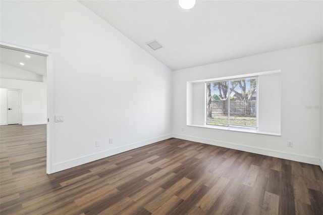 spare room with dark wood-type flooring and lofted ceiling