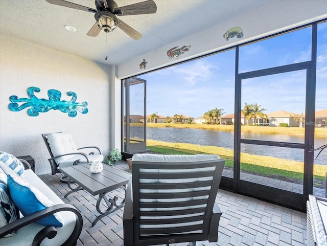 sunroom featuring ceiling fan and a water view