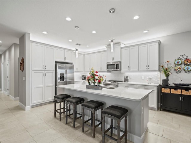 kitchen featuring pendant lighting, a kitchen bar, stainless steel appliances, and an island with sink