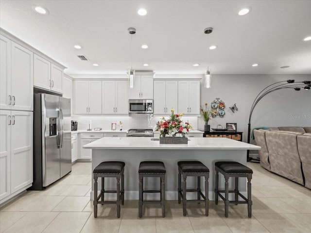 kitchen featuring pendant lighting, a center island, a kitchen bar, and appliances with stainless steel finishes