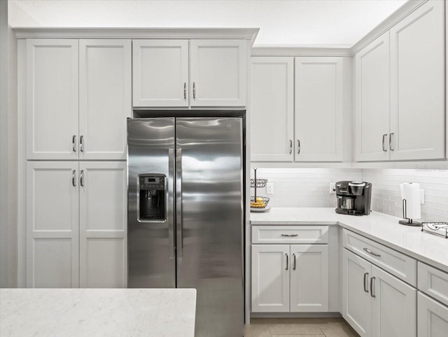 kitchen featuring stainless steel fridge, light stone countertops, and tasteful backsplash