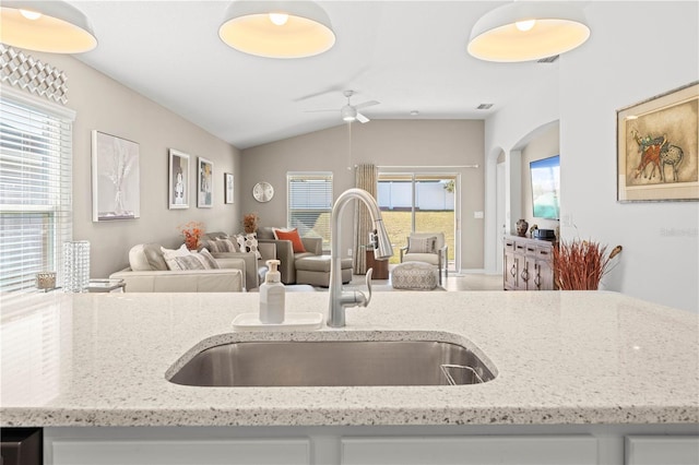 kitchen featuring vaulted ceiling, sink, a wealth of natural light, and light stone counters