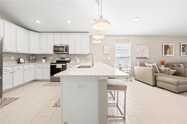 kitchen featuring appliances with stainless steel finishes, decorative light fixtures, sink, white cabinets, and light stone counters