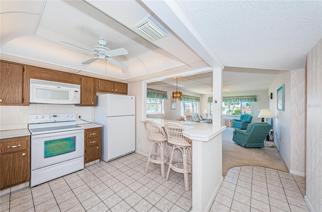 kitchen with white appliances, light carpet, decorative light fixtures, kitchen peninsula, and a breakfast bar area