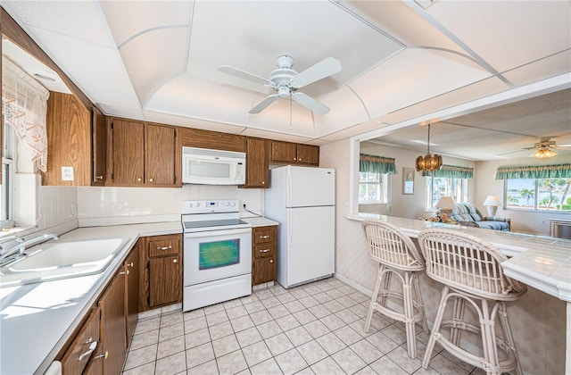 kitchen with ceiling fan, sink, hanging light fixtures, and white appliances