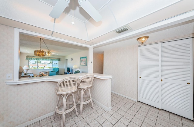 kitchen with ceiling fan, light tile patterned floors, a breakfast bar area, and kitchen peninsula