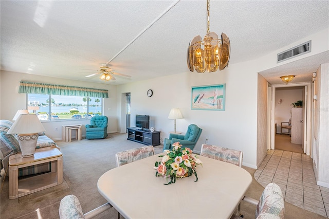 dining space with carpet flooring, ceiling fan with notable chandelier, and a textured ceiling